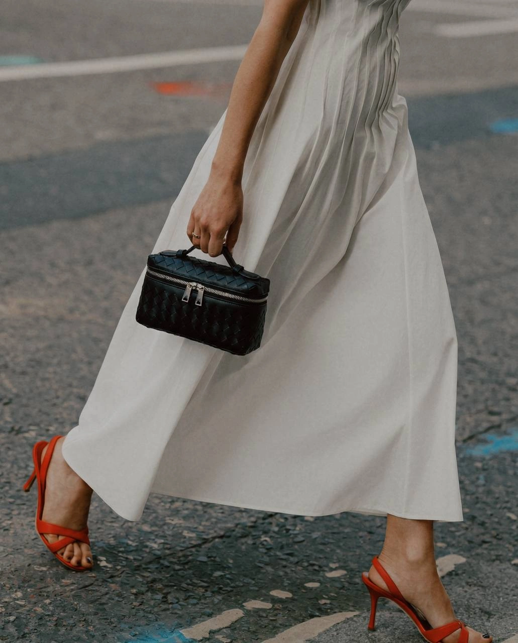 Accessory detail: a woven bag and white dress